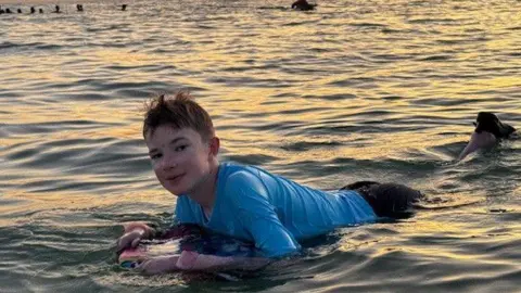 GOSH Gabrielius Misurenkovas swimming in the sea with a body board and a sunset