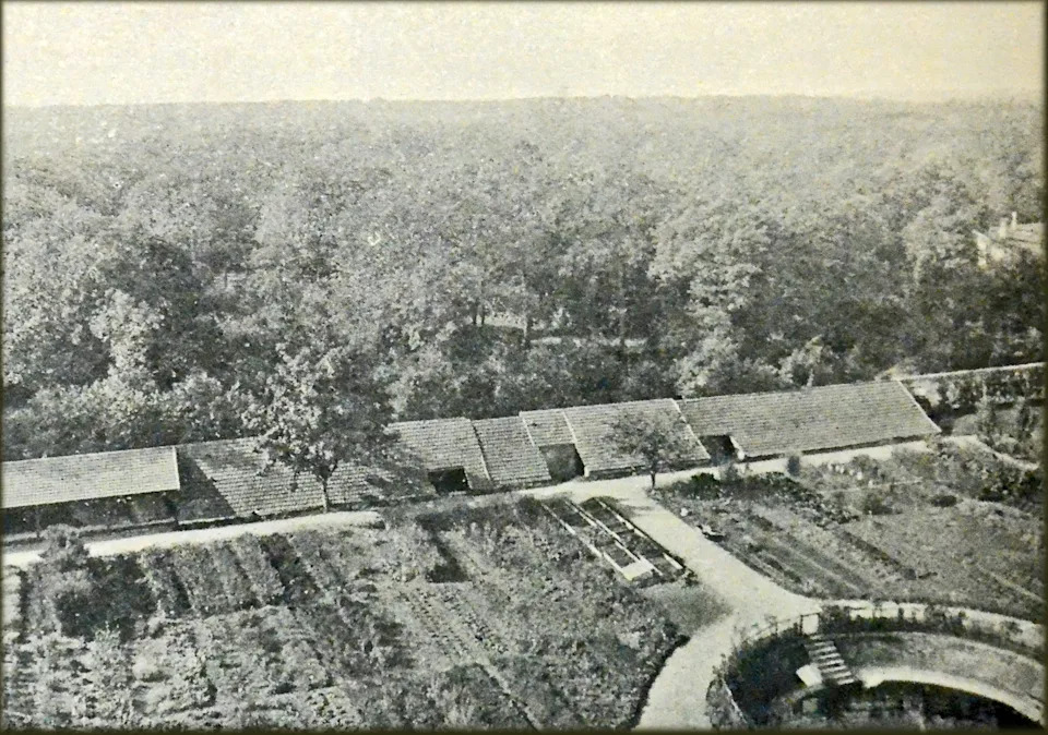 A black-and-white aerial photograph of Daniel Berthelot’s experimental field in Meudon, France, showing rows of garden plots, greenhouses with tiled roofs, and a circular structure at the bottom right.