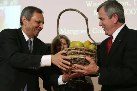 AFP via Getty Images  Indian Ambassador Ronen Sen (L) hands a basket of Indian mangoes to US Agriculture Secretary Mike Johanns at a ceremony celebrating the opening of mango trade between the United States and India at the Commerce Department in Washington 01 May 2007. 