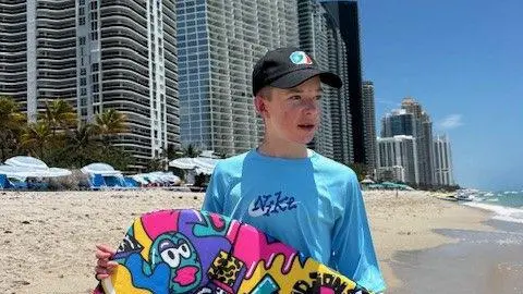 GOSH Gabrielius Misurenkovas at the beach holding a body board