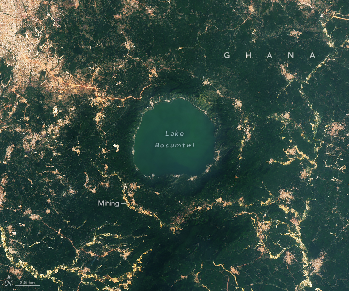 A satellite image taken in 2024 also shows Lake Bosumtwi. The 2024 image looks similar to the 2015 view but shows more cleared land around the lake and greener water.