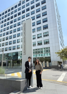 two people smiling in front of a building