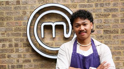 A portrait image of a contestant stood against an exposed brick wall, with the MasterChef logo behind him.