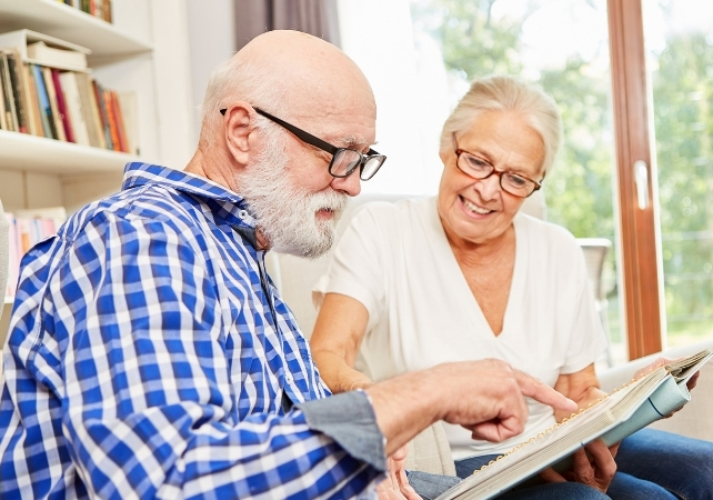 elderly man looking at a book with a partner