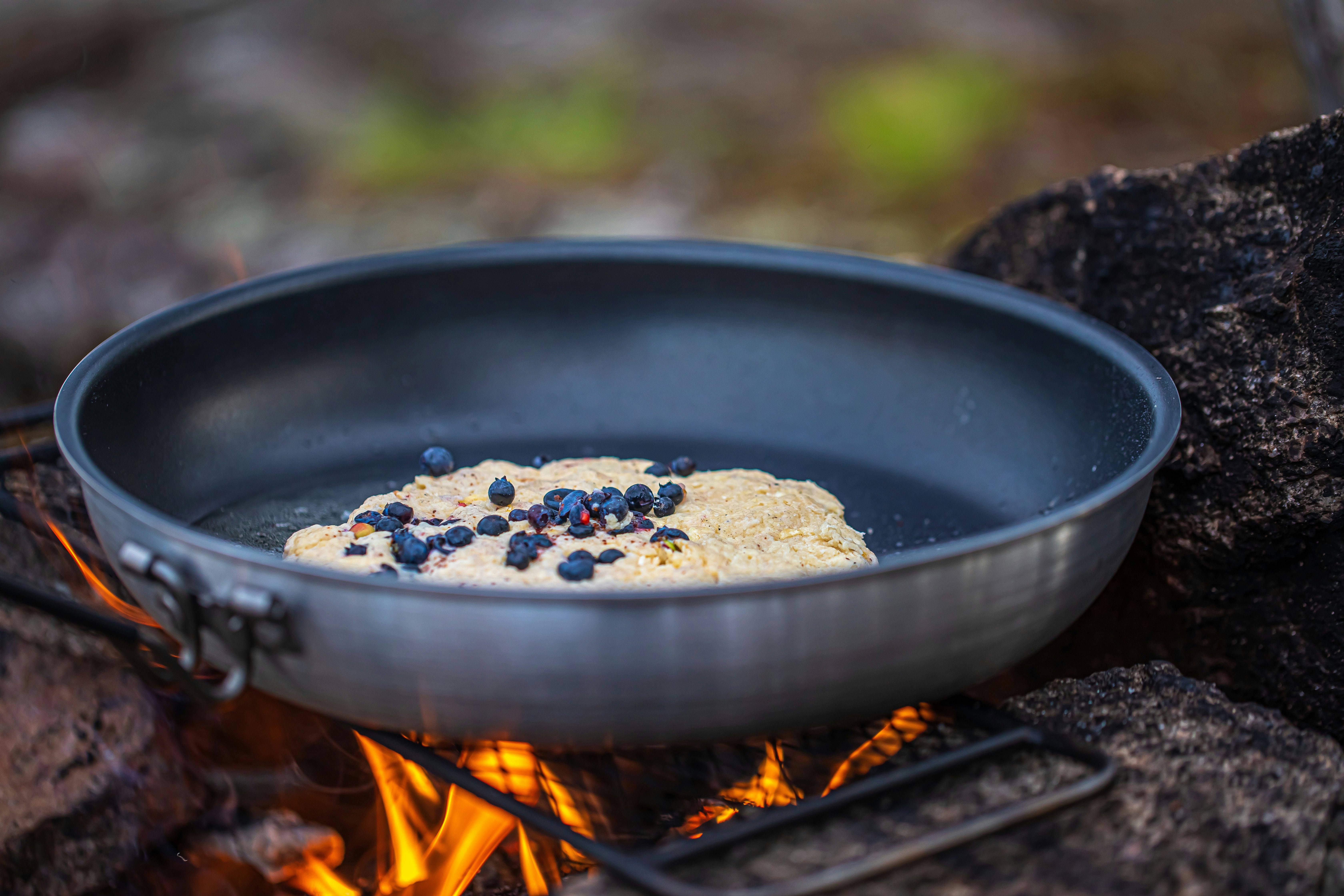 Blueberry bannock over a campfire, cooking in camp.