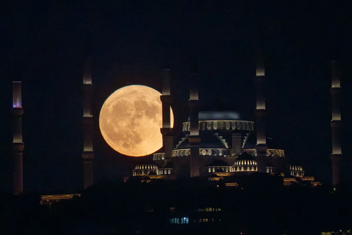 The Sturgeon full moon rises behind Istanbul's Camlica Mosque on 1 August 2023 in Istanbul, Turkey. Photo by Chris McGrath/Getty Images