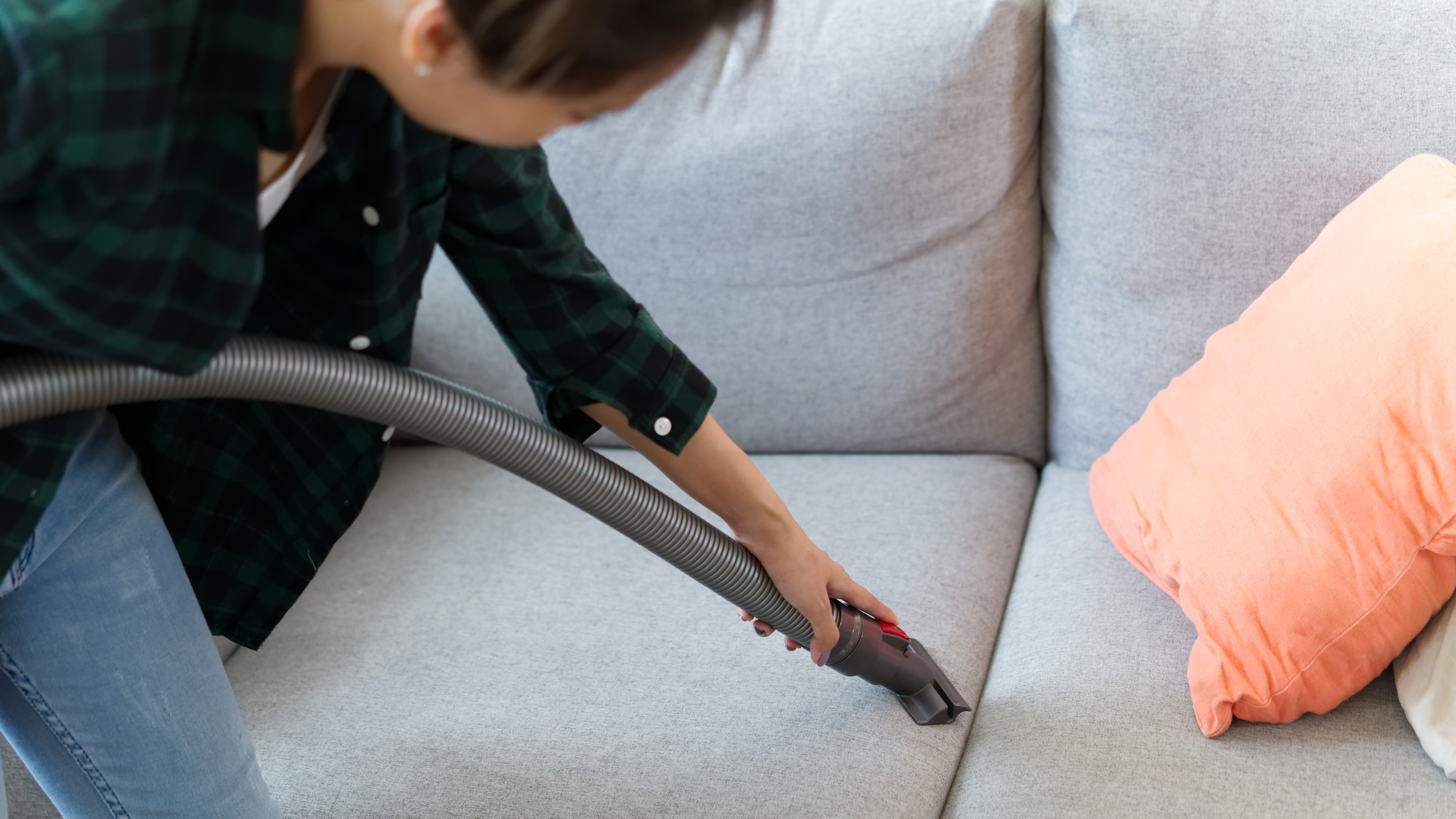 Woman cleaning sofa with attachment