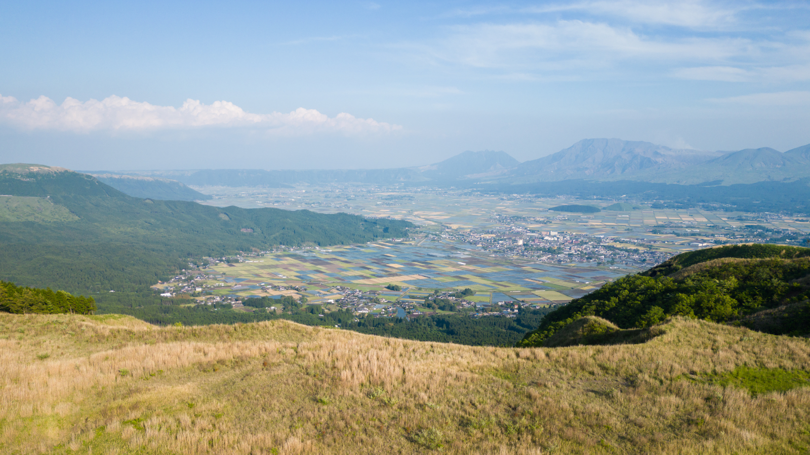 A photo taken from the top of the caldera's ridge, showing the ventral volcanoes in the distance surrounded by urban development and agricultural fields