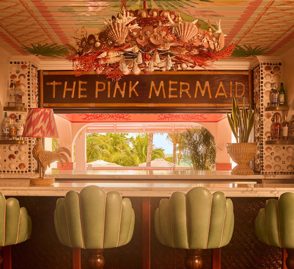 The Pink Mermaid bar in the Bahamas, featuring a seashell chandelier and green barstools.
