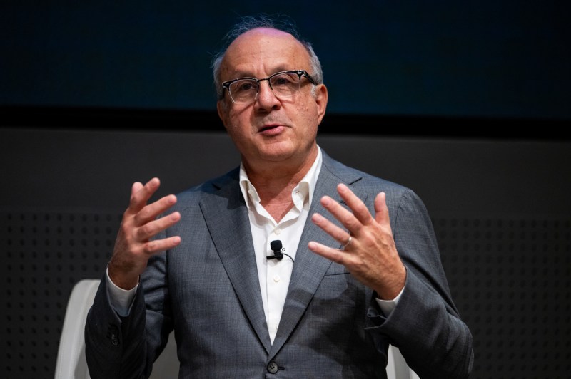 A man in a suit gestures while speaking during a fireside chat at Northeastern University’s Senior Leadership Retreat.