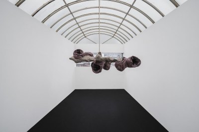 View of a sculpture hanging in the center of a white cube gallery with a domed roof.