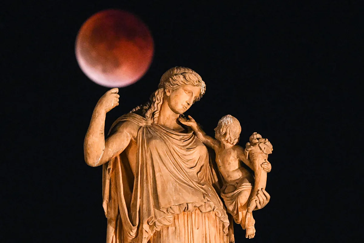 Blood Moon total lunar eclipse over a statue of the ancient Greek goddess Irene, central Athens, 7 September 2025. Photo by ANGELOS TZORTZINIS/AFP via Getty Images