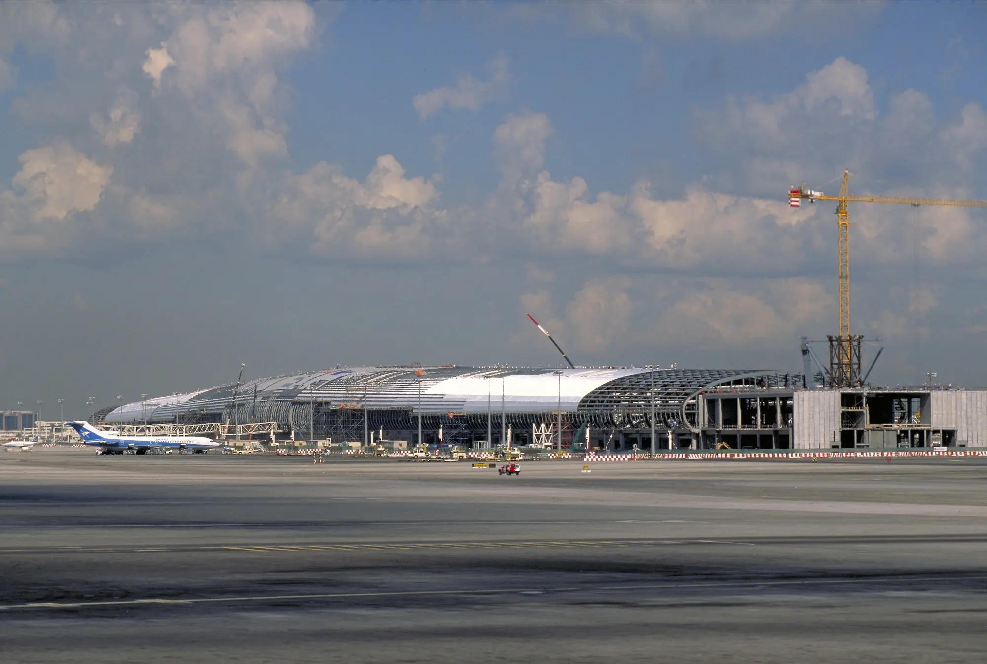 Concourse shown under construction with cranes and blue skies in background.