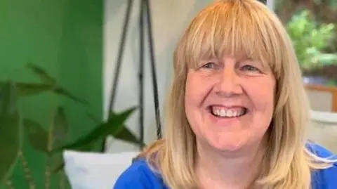 Mary Delargy Mary Delargy smiling at the camera, she has blonde hair and is wearing a blue top. 