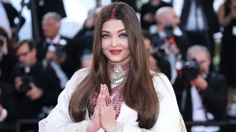 Getty Images Indian actress Aishwarya Rai Bachchan, wearing a white saree and heavy jewellery with folded hands. 