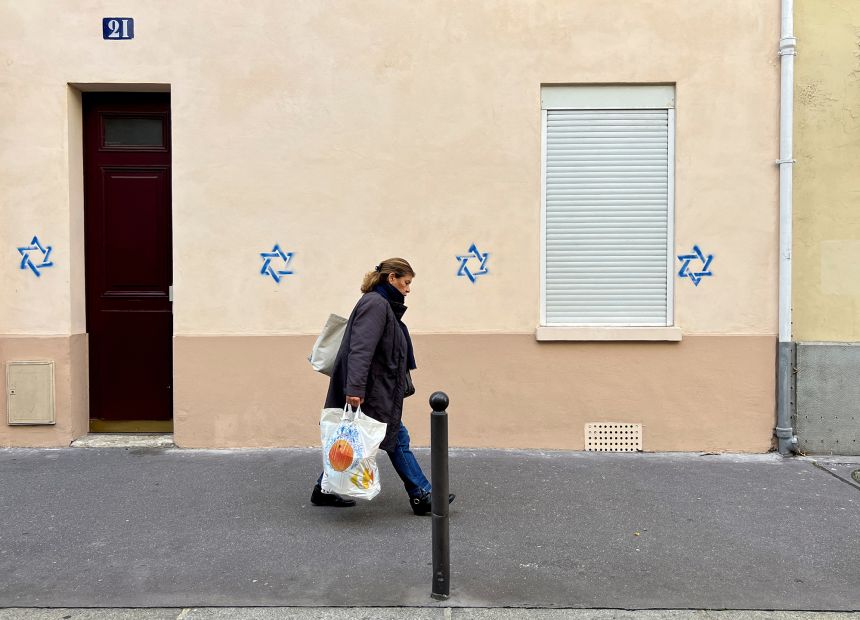 A woman walks past a building tagged with Stars of David in Paris on October 31, 2023.
