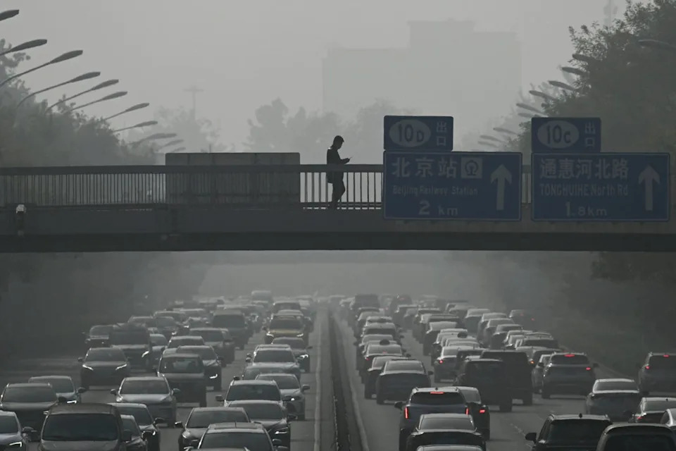 Pedestrians walk on an overpass amid haze from air pollution in Beijing in 2023 (AFP via Getty Images)