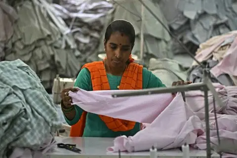AFP via Getty Images A garment worker sorts tailored shirts at an apparel manufacturing unit in Bengaluru on August 25, 2025.