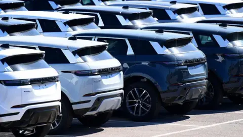 Getty Images A row of brand new Range Rover cars, some white and some black, standing outside the Jaguar Land Rover factory in Halewood, England
