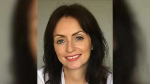 Frances Maguire Frances has long dark hair and is smiling at the camera. She is wearing makeup with a pink lipstick, and is wearing a white shirt.