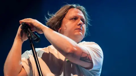 Getty Images A photo of Lewis Capaldi on stage holding a microphone stand