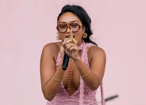 Joy Crookes holds a finger up to the camera as she performs on stage at the 2025 Reading Festival