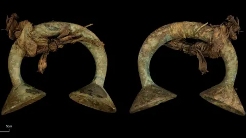 Guard Archaeology The curved cup-ended ornament photographed against a black background.