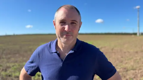 BBC Nottinghamshire farmer Patrick Lynn stood in a field wearing a navy polo shirt