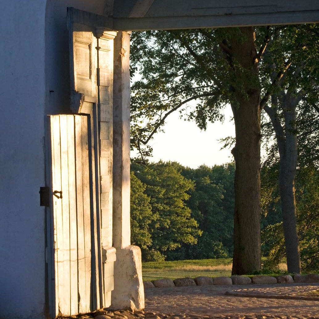 Open doorway framed by an arch, leading to a natural landscape.