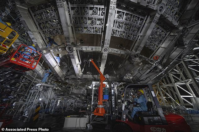 Workers labor on the underside of the cosmic detector. This futuristic underground observatory has been built with the sole purpose of detecting neutrinos – tiny cosmic particles with a mind-bogglingly small mass