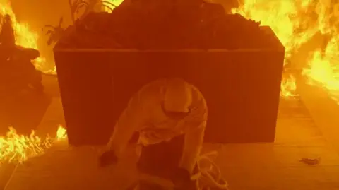 YouTube.com/@MrBeast A man escaping a coil of rope in a burning building.