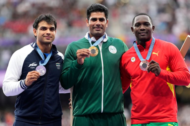 Men's javelin gold medalist, Arshad Nadeem, centre, of Pakistan, stands with silver medalist, Neeraj Chopra, of India, and bronze medalist, Anderson Peters, right, of Grenada, on the podium at the 2024 Summer Olympics, Friday, Aug. 9, 2024, in Saint-Denis, France. (AP Photo/Bernat Armangue)