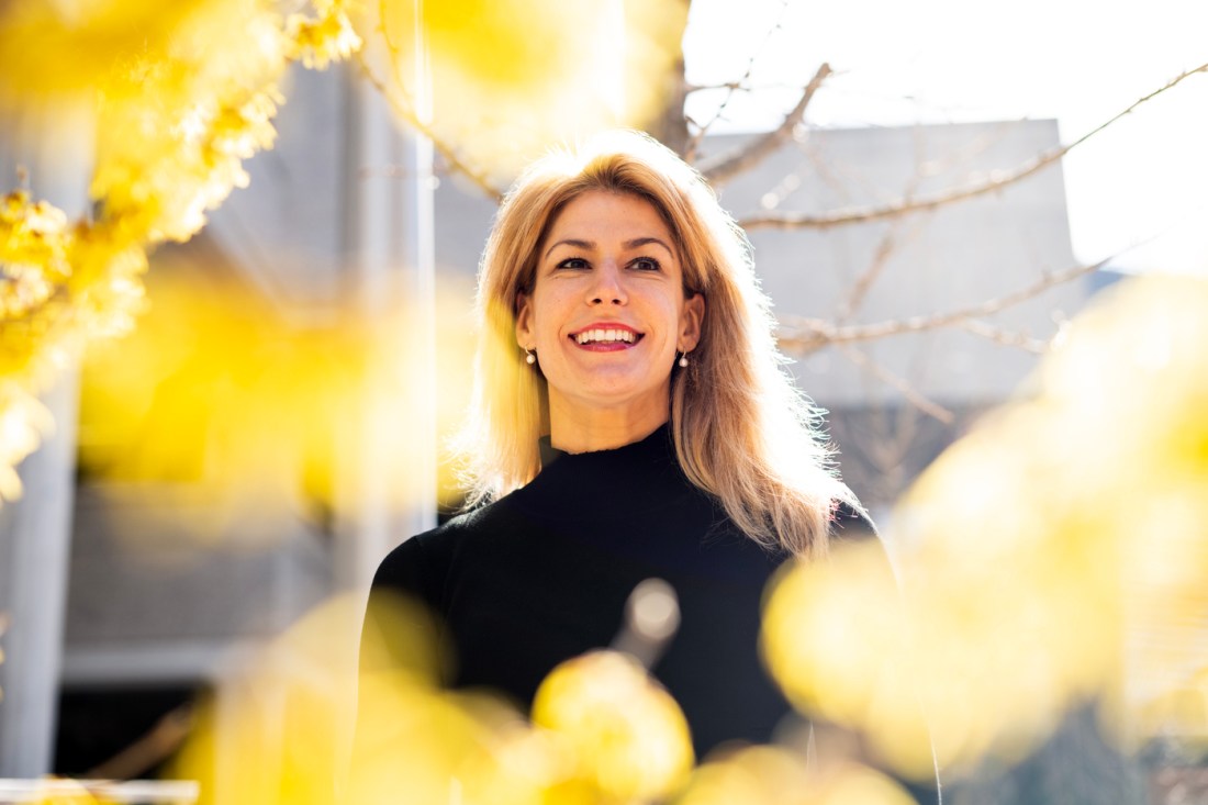 Elizabeth Glowacki, an assistant teaching professor, depicted in a black dress between fall foliage.