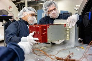 Engineering technologist Adolfo Salazar, left, and systems engineer Sean Walker prepare a sensor from the IIIF Global Burst Detector for thermal vacuum testing. (Photo by Bret Latter) Click on the thumbnail for a high-resolution image.