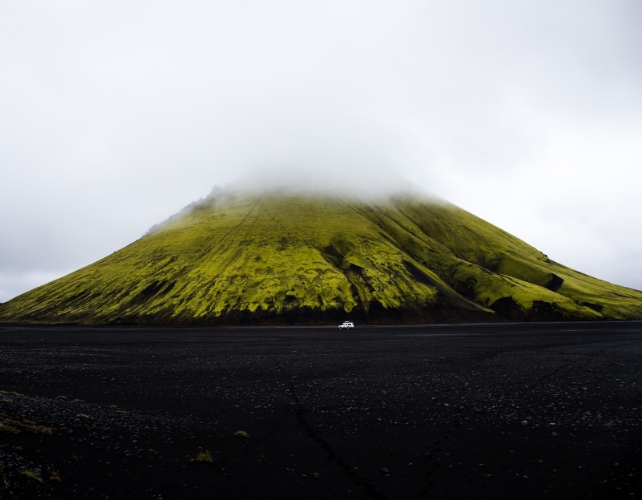 Misty clouds floating over a green volcano 