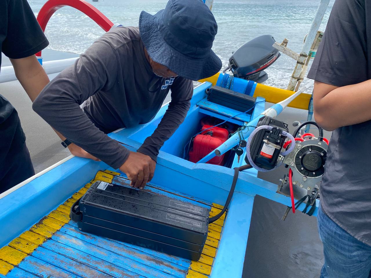 A fisherman in Klungkung checks the condition of his electric boat engine.