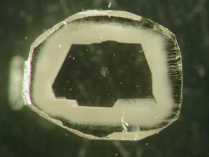 Slice of African diamond with a clear core and cloudy, inclusion-rich rim