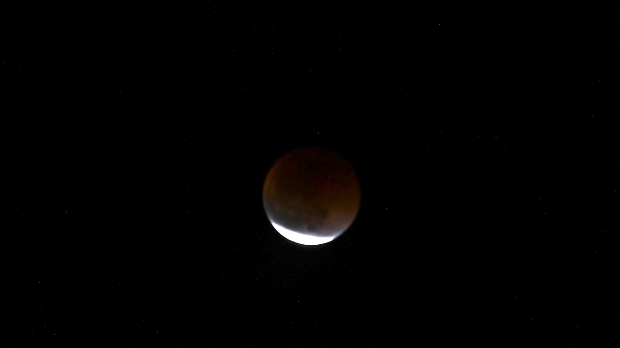 photo of a lunar eclipse, showing the moon shining a dull red color