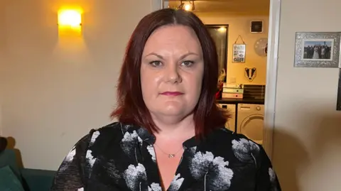 BBC Kerry McDermott pictured at home with a kitchen in the background and a phot frame with a silver sparkly frame 