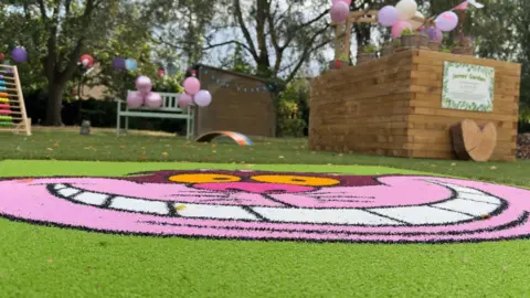 A very low-angled shot of The Cheshire Cat from Disney's Alice in Wonderland painted onto an artificial grass pitch
