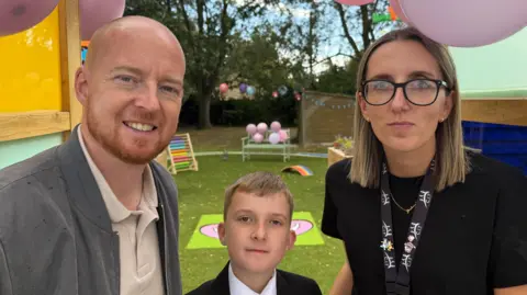 BBC Joshua in his school uniform is flanked by his parents