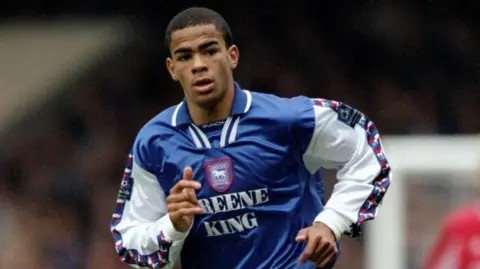 Getty Images Kieron Dyer wearing an Ipswich Town football shirt while playing. It has the logo and the Greene King sponsor on the front of it.