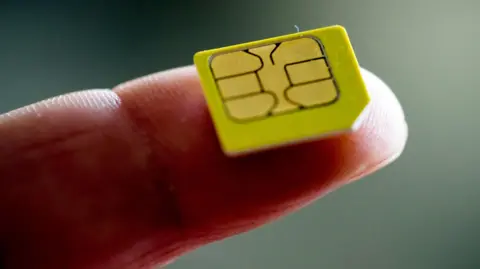 Getty Images A sim card on a person's finger