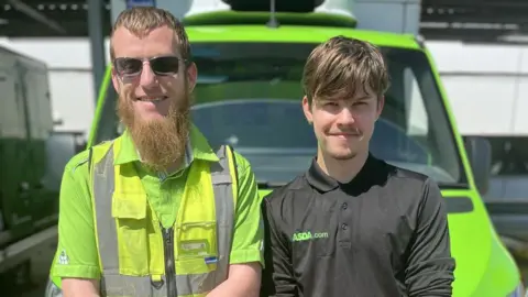 ASDA Two male ASDA delivery drivers leaning on the hood of a green delivery van and smiling at the camera. Allan, on the left, is wearing sunglasses and a bright green t-shirt underneath a yellow hi-vis vest. He has light brown hair and a long beard. The man on the right has dark brown hair, faint facial hair and is wearing a black branded ASDA polo shirt.