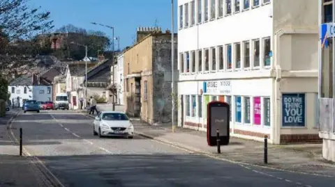 UIC An artist's impression shows a larger than life model of a mobile phone on City Road in Truro. A white car is driving along the road.
