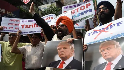 Hindustan Times via Getty Images Members of Federation of Sadar Bazar Trades Association raise slogans with Donald Trump's photos during a protest against the recent tariffs in New Delhi, India.