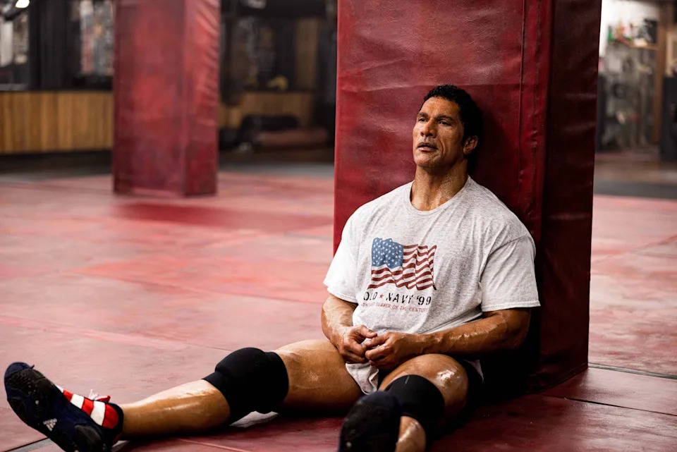 Dwayne Johnson leans against a column in a scene in The Smashing Machine.