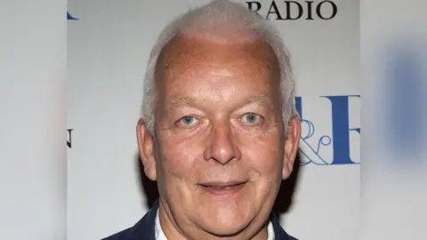 Getty Images Close up of Andrew Davies pictured at a screening of the highlights of "Bleak House" hosted by the Museum of Television & Radio and Produced by the BBC in WGBH Boston and Masterpiece Theatre on June 8, 2006 in West Hollywood, California. He has short white hair and is smiling looking at the camera.