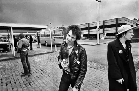 Dennis Morris Black and white photograph of Sid Vicious and Johnny Rotten of The Sex Pistols standing at a bus station