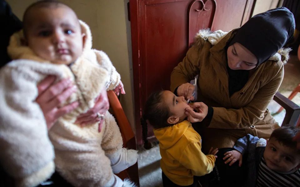 A girl receives receives an oral cholera vaccine from Lebanese Red Cross (LRC) staff in her home in Bebnine